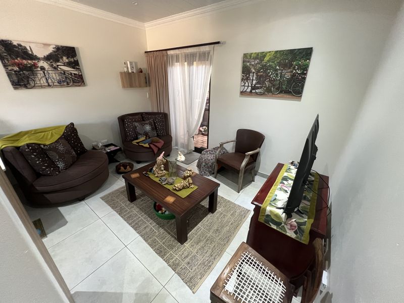 A comfortable living room featuring tiled flooring, crown molding, and sliding glass doors providing direct access to an outdoor patio area.