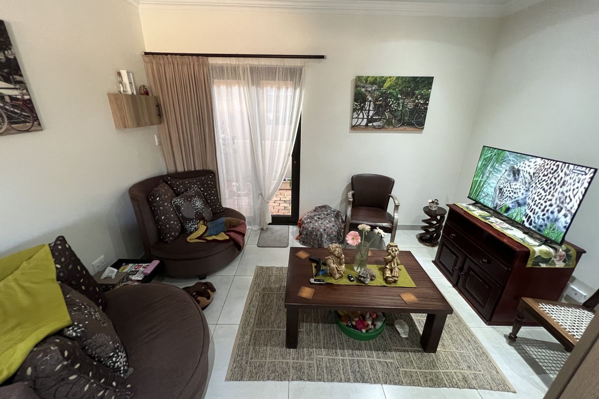 A comfortable living room featuring tiled flooring, crown molding, and sliding glass doors that provide access to an outdoor patio area.