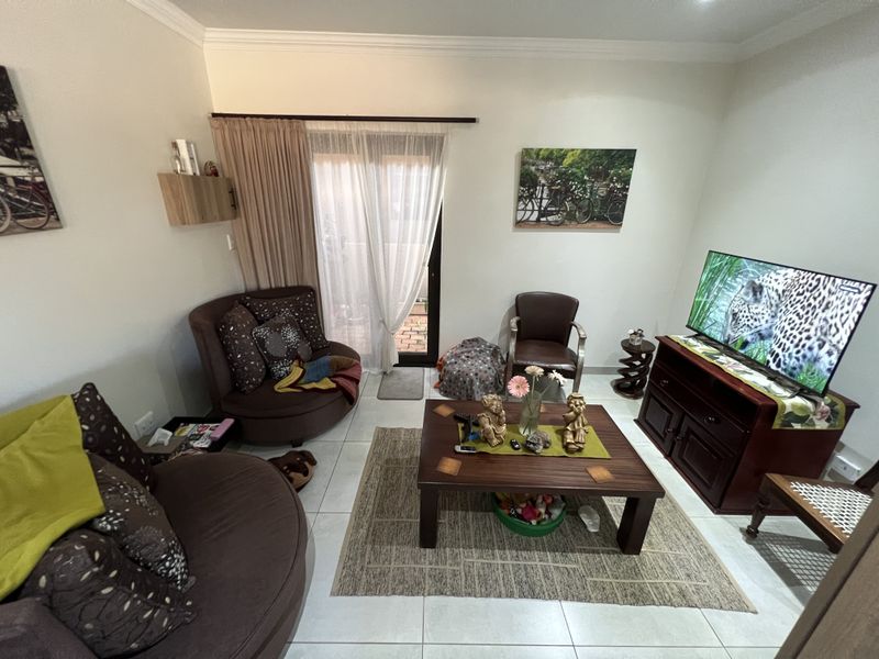 A comfortable living room featuring tiled flooring, crown molding, and sliding glass doors that provide access to an outdoor patio area.