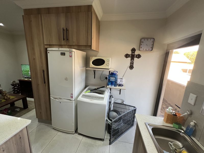 A functional laundry area featuring built-in cabinetry, a stainless steel sink, and dedicated space for a washing machine.