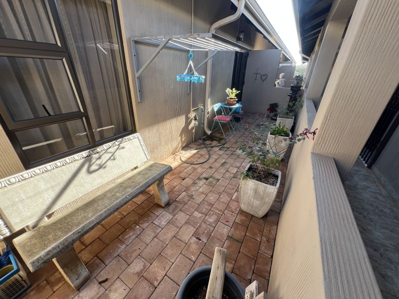 A private, paved patio area featuring a built-in stone bench, wall-mounted drying rack, and external water tap, ideal for outdoor relaxation.