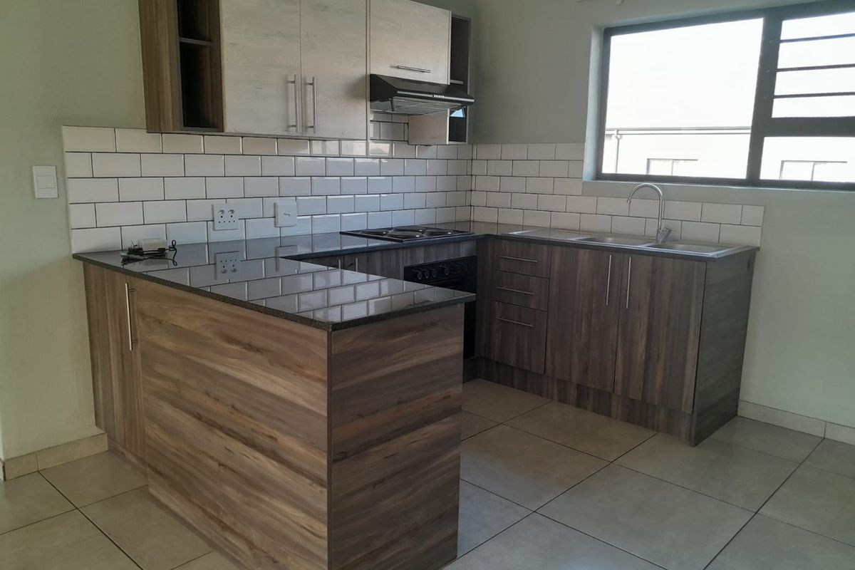 Modern kitchen featuring dark wood cabinetry, granite countertops, subway tile backsplash, built-in oven, hob, and extractor fan with tiled flooring.