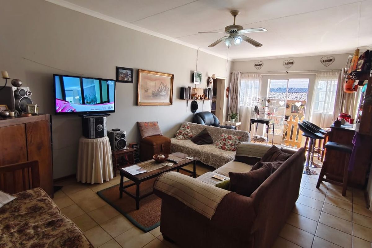 A comfortable living room featuring tiled flooring, a ceiling fan, and sliding glass doors that provide access to the outdoor area.