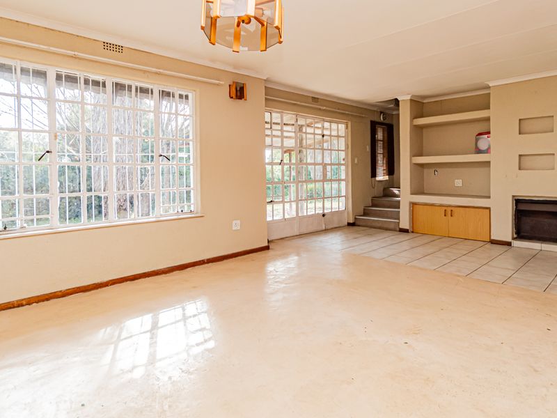 Spacious living room featuring built-in shelving, a fireplace, tiled flooring, and large windows that provide ample natural light.