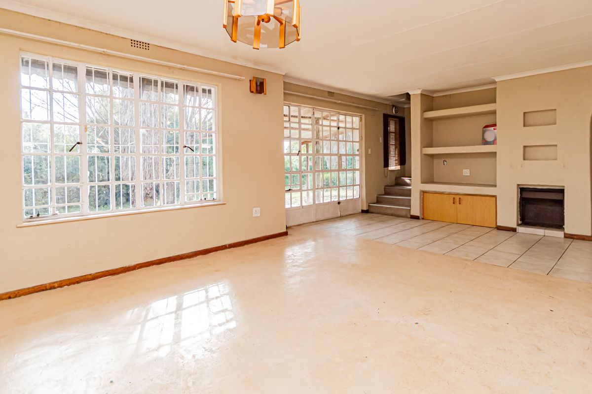 Spacious living room featuring built-in shelving, a fireplace, tiled flooring, and large windows that provide ample natural light.