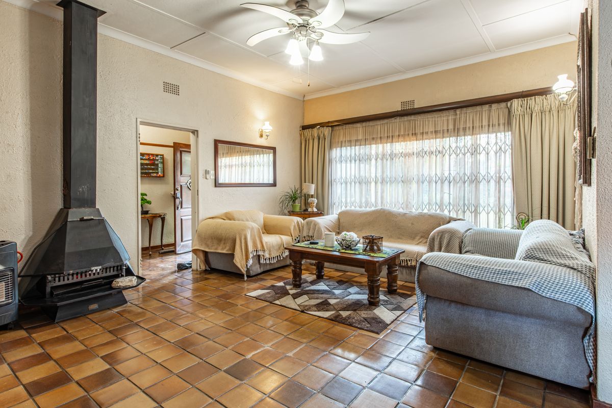 Spacious living room featuring a built-in fireplace, tiled flooring, ceiling fan, and large windows with security gates.