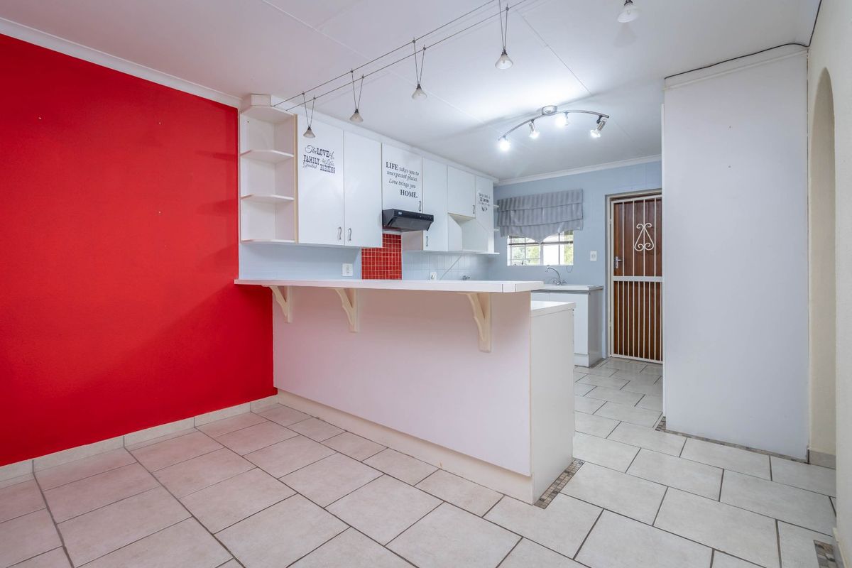 A functional kitchen featuring built-in cabinetry, a breakfast bar, tiled flooring, and an integrated extractor fan, offering a clean and practical layout.