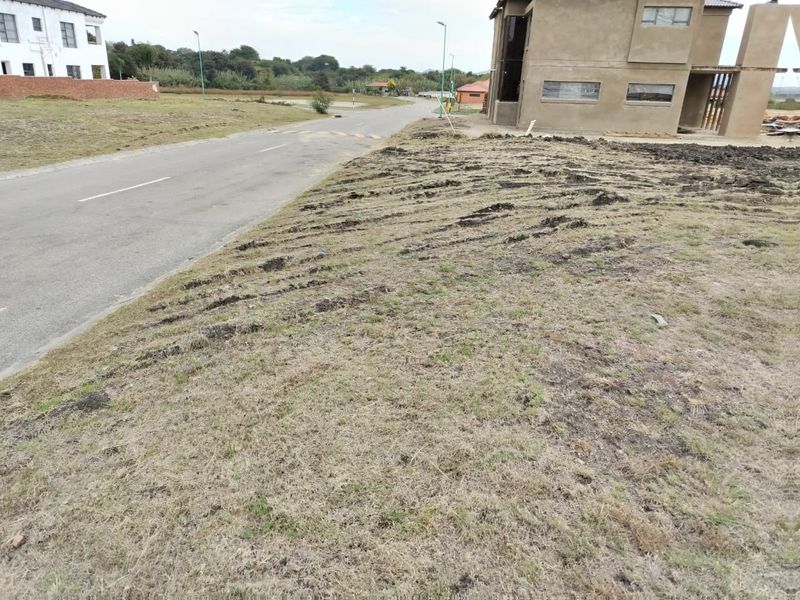 A view of the street frontage and adjacent vacant residential land showing natural terrain and proximity to existing neighborhood infrastructure.