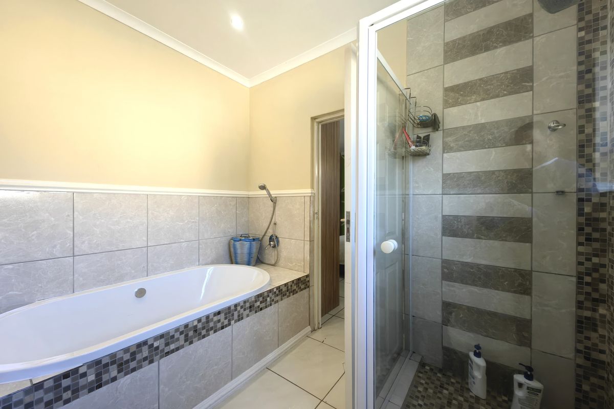 A well-maintained bathroom featuring a built-in bathtub, a separate shower enclosure with tiled finishes, and neutral wall tones.
