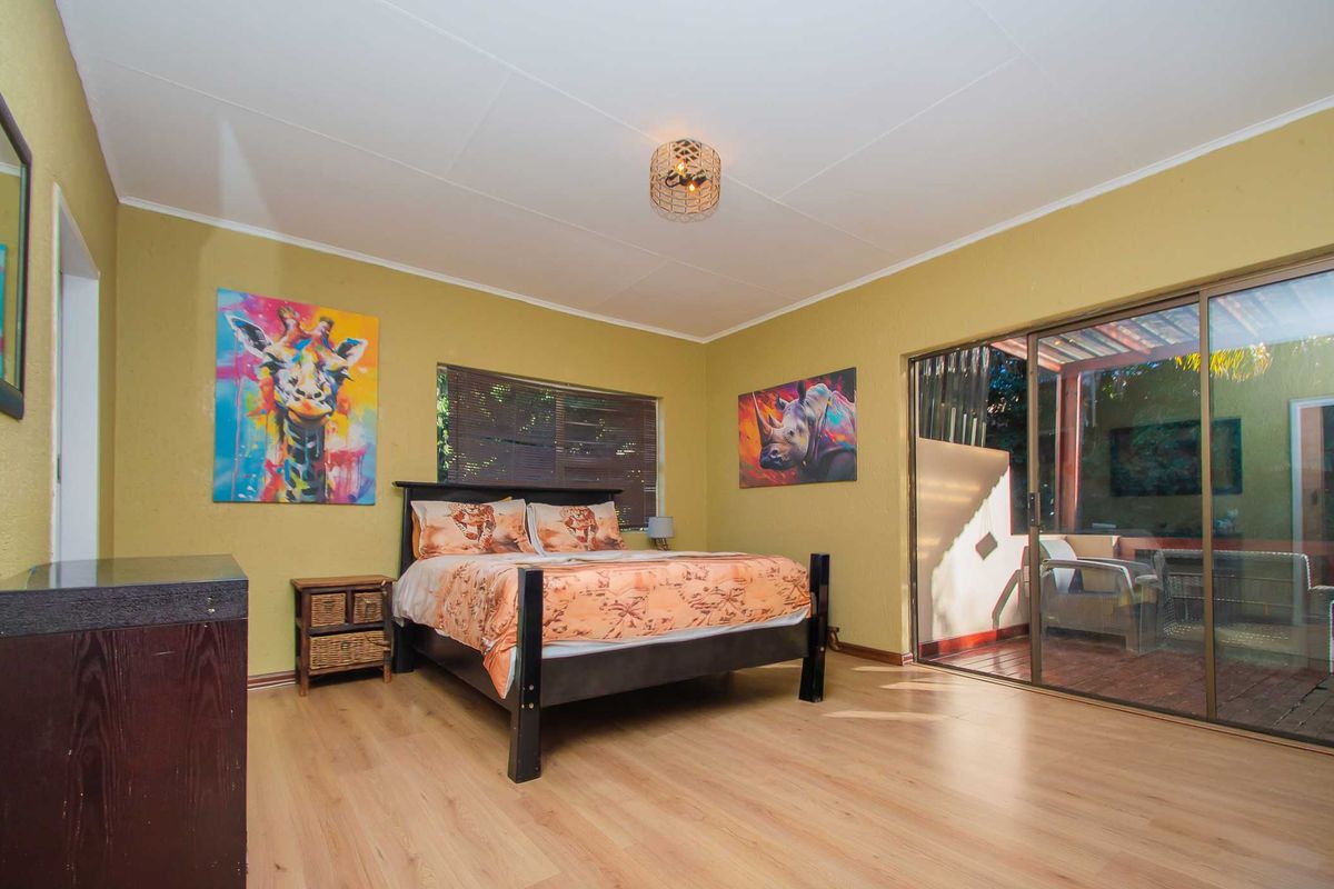 Spacious bedroom featuring light laminate flooring and a large sliding glass door providing direct access to an outdoor patio area.