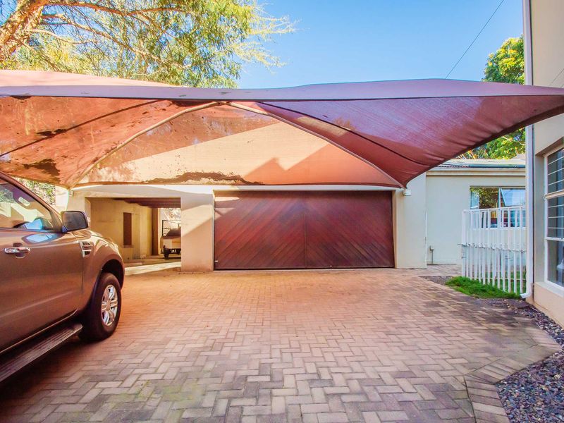A paved driveway area featuring a large shade sail structure and a double timber garage door.