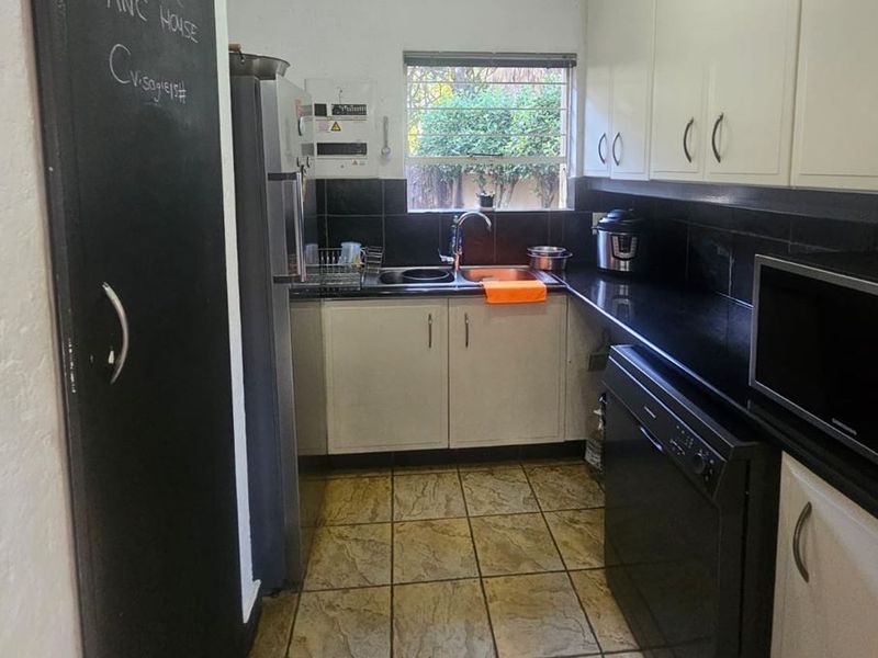 A functional kitchen featuring built-in cabinetry, stone countertops, a double sink, and tiled flooring with a classic black and white aesthetic.