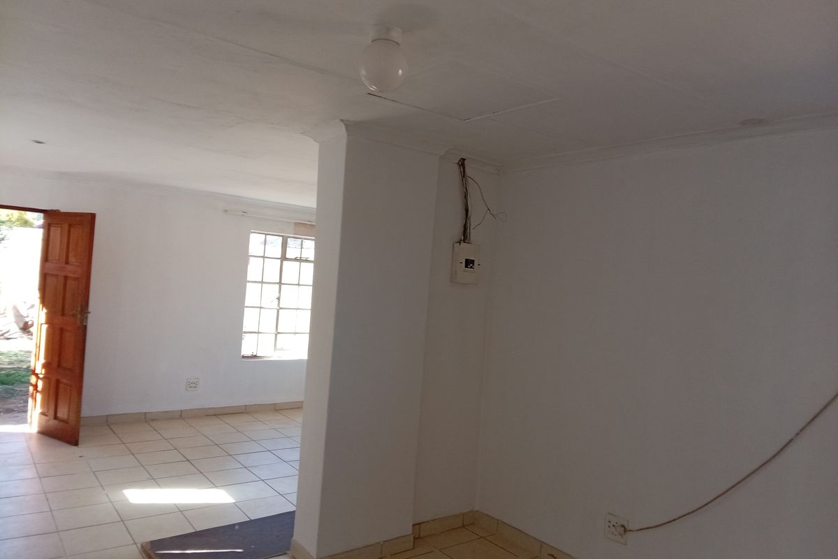 An empty, open-plan living area featuring tiled flooring and exposed electrical infrastructure, offering a blank canvas for renovation and interior design.
