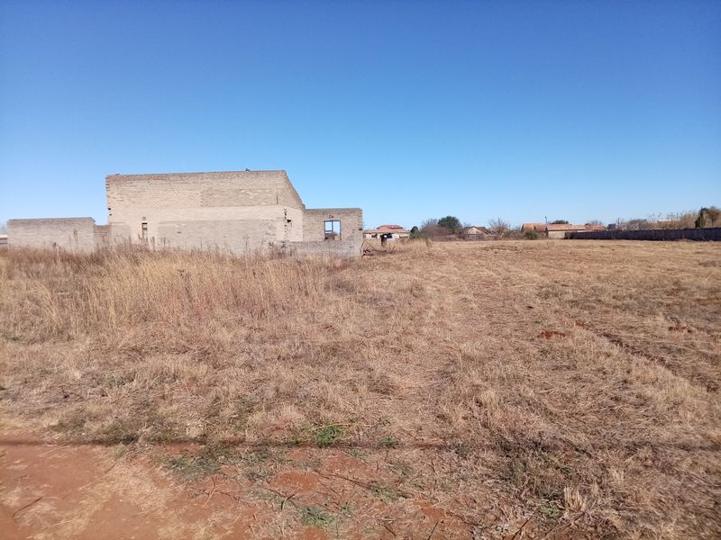 A large plot of land featuring an incomplete brick structure, offering significant potential for development or custom construction projects.
