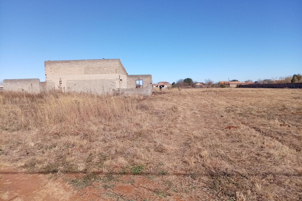 A large plot of land featuring an incomplete brick structure, offering significant potential for development or custom construction projects.