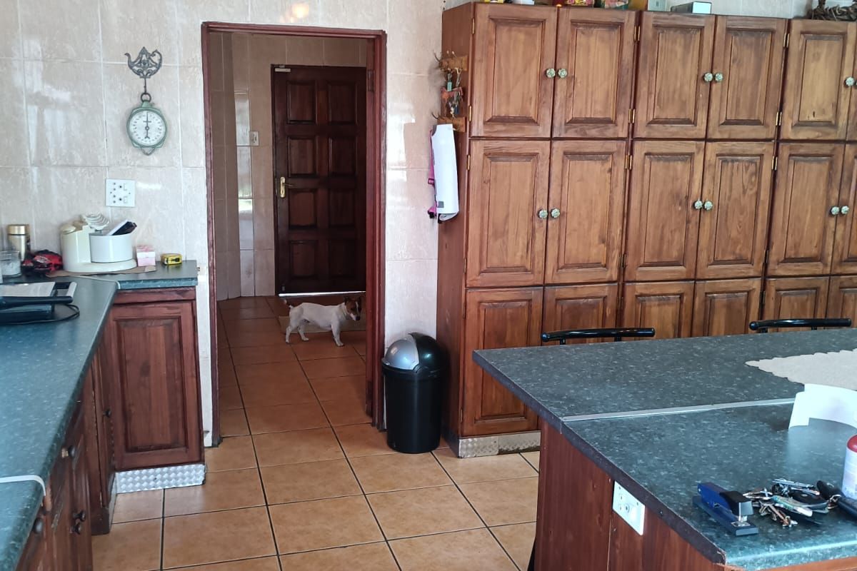 A functional kitchen featuring extensive wooden cabinetry, tiled wall finishes, and durable floor tiles, offering a traditional layout with ample storage space.