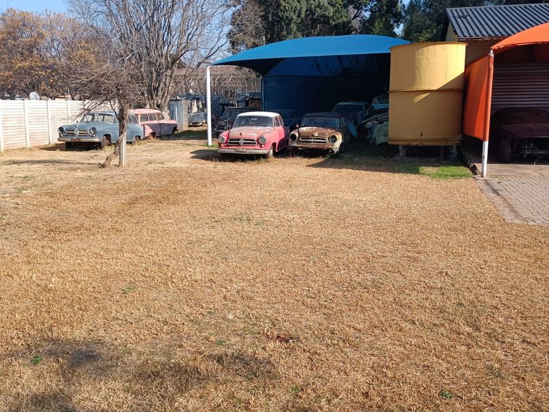 Rear yard area featuring a shade sail structure, water tank, and paved driveway access.