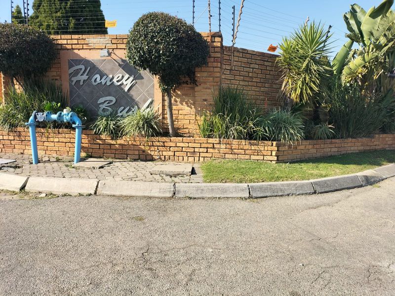 Exterior view of the complex entrance featuring a brick boundary wall, electric fencing, and a prominent fire hydrant.