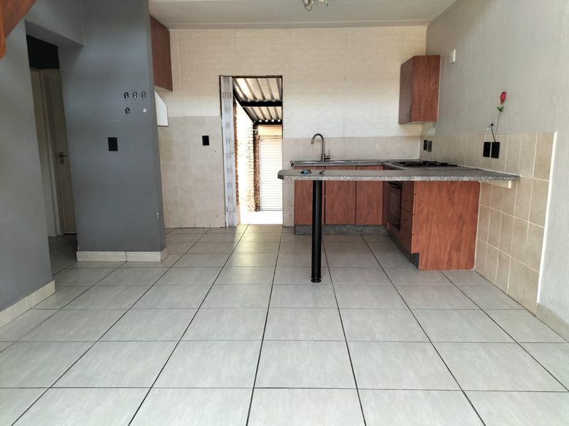 A functional kitchen area featuring built-in wooden cabinetry, granite countertops, and tiled flooring, offering a blank canvas for potential modern updates.