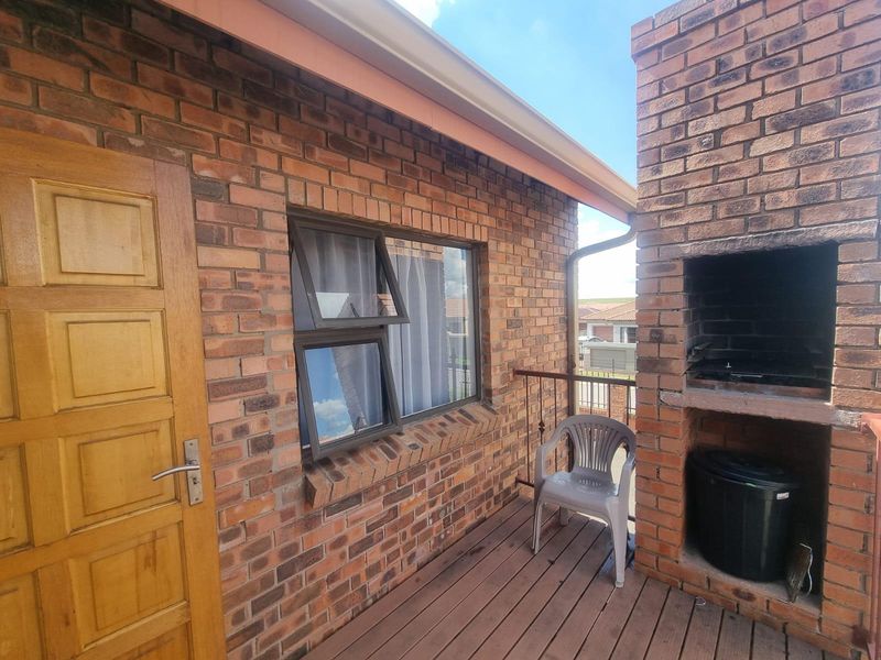 A private balcony featuring a built-in brick braai, wooden decking, and direct access to the interior through a solid timber door.