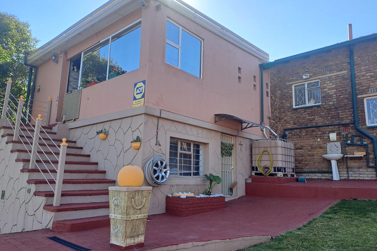Rear exterior view showing a paved patio area, external staircase, water storage tank, and a brick and plastered building facade.