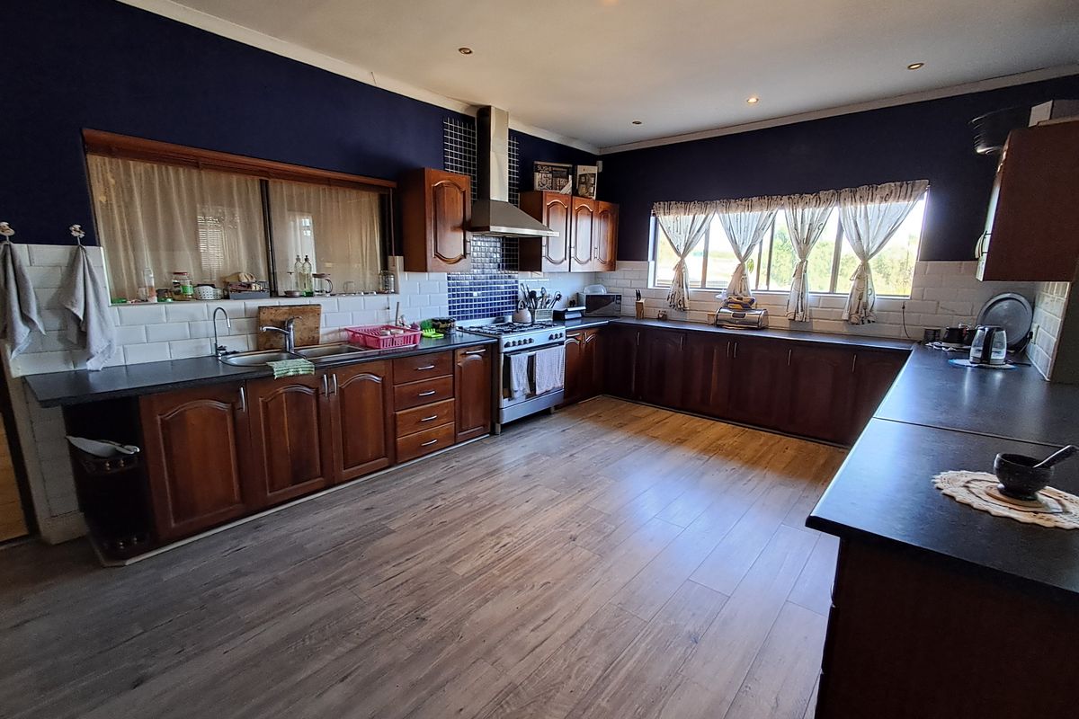 Spacious kitchen featuring dark wood cabinetry, laminate countertops, a gas stove with extractor fan, and subway tile backsplash with modern laminate flooring.