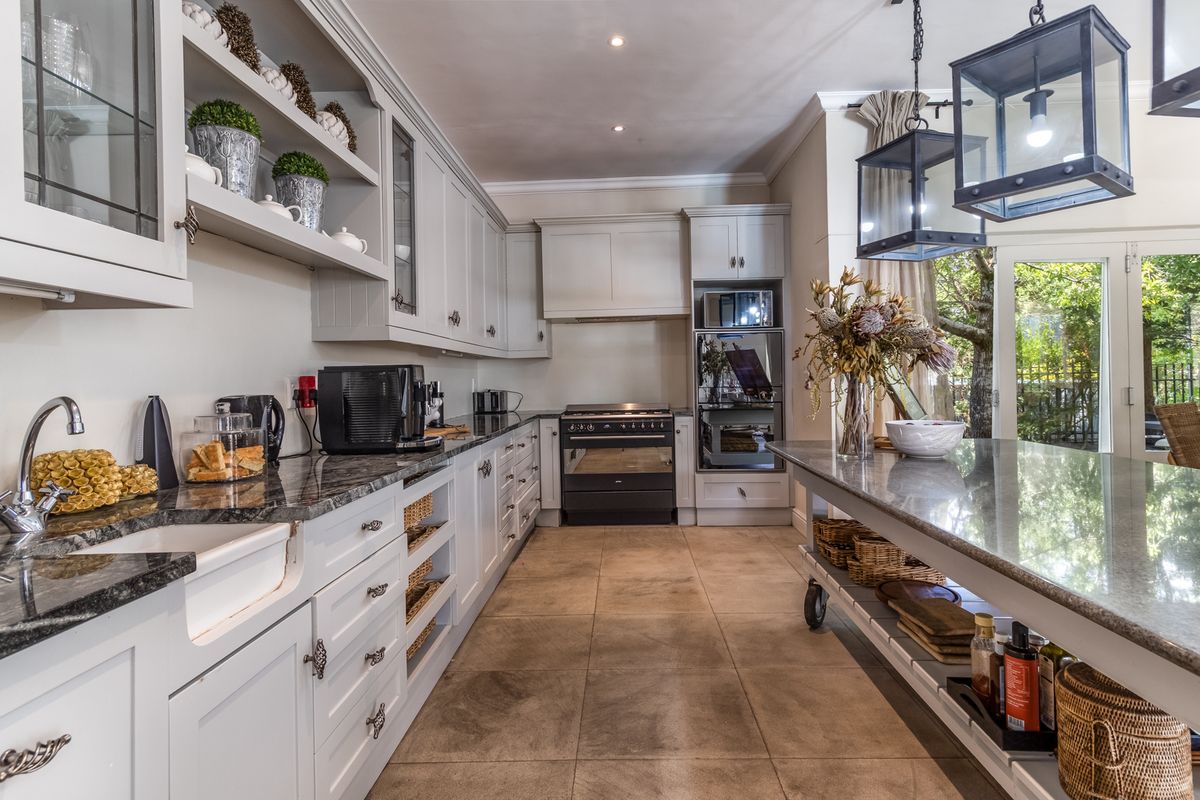 A well-appointed kitchen featuring granite countertops, a farmhouse sink, built-in oven, gas stove, and a central island with pendant lighting.