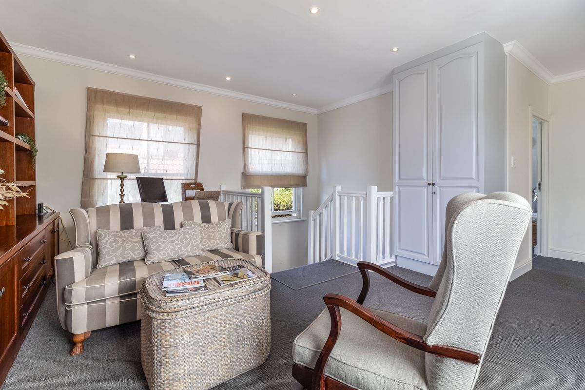 A well-maintained living area featuring built-in cabinetry, a built-in wardrobe, and a staircase balustrade, finished with neutral tones and recessed lighting.