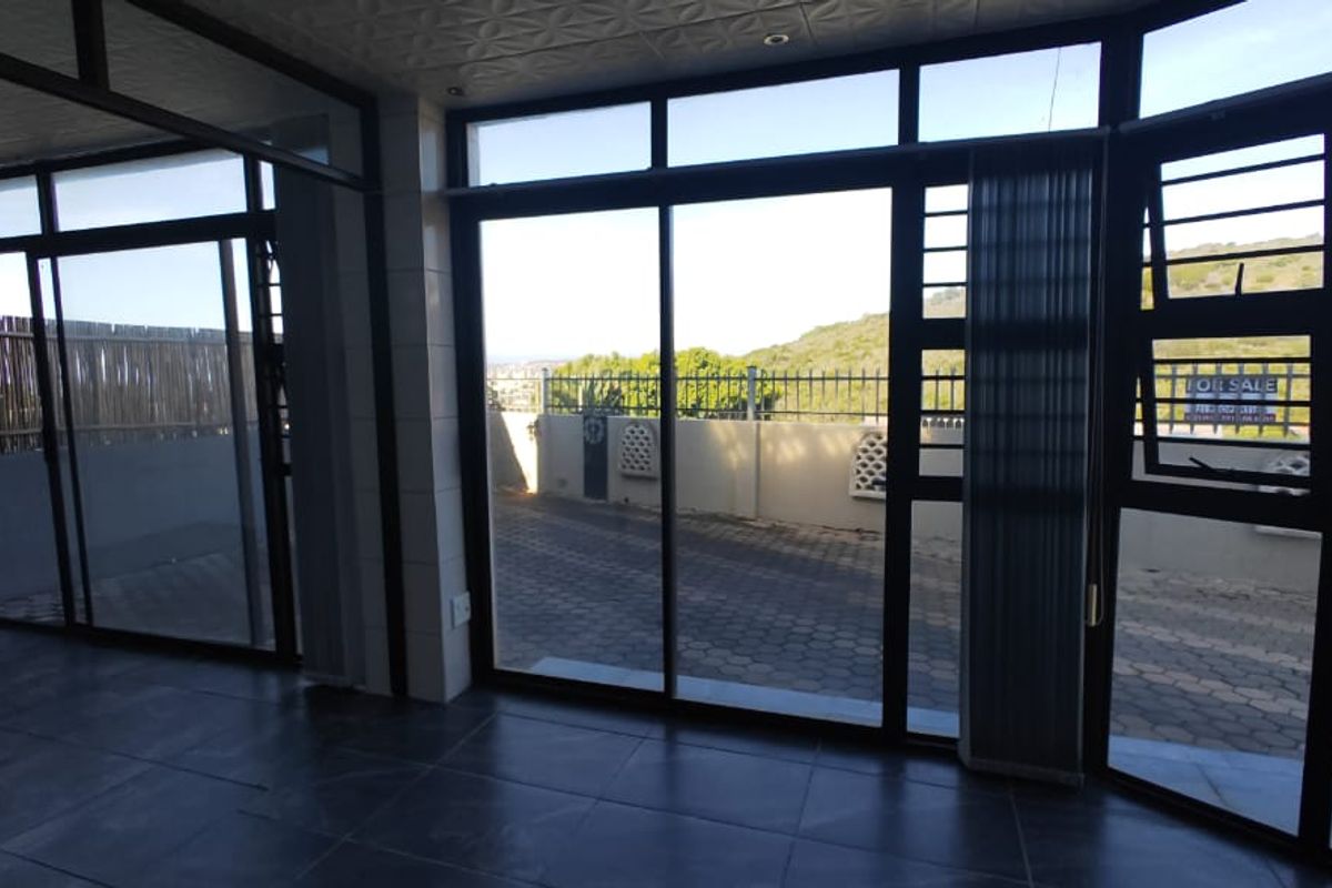 Spacious, light-filled living area featuring large sliding glass doors that provide seamless access to the outdoor paved patio and garden area.