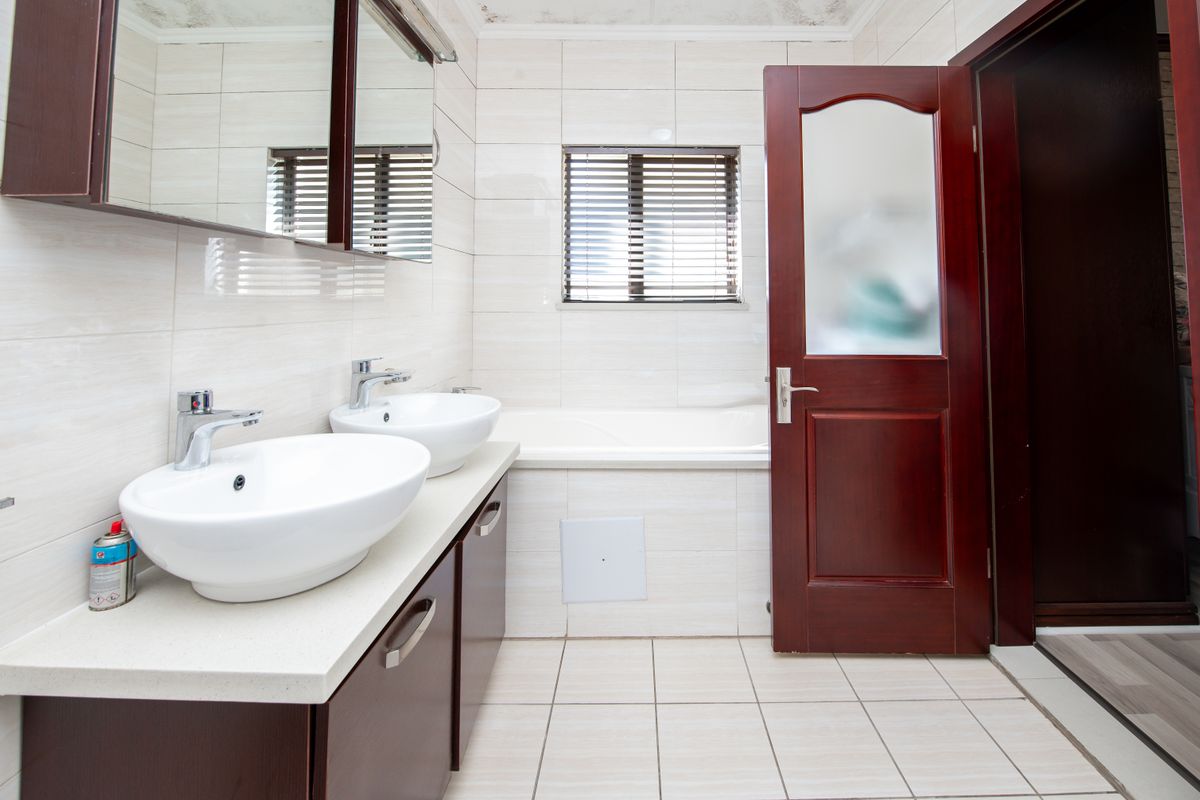 A functional bathroom featuring a double vanity with vessel sinks, a built-in bathtub, and tiled finishes throughout.