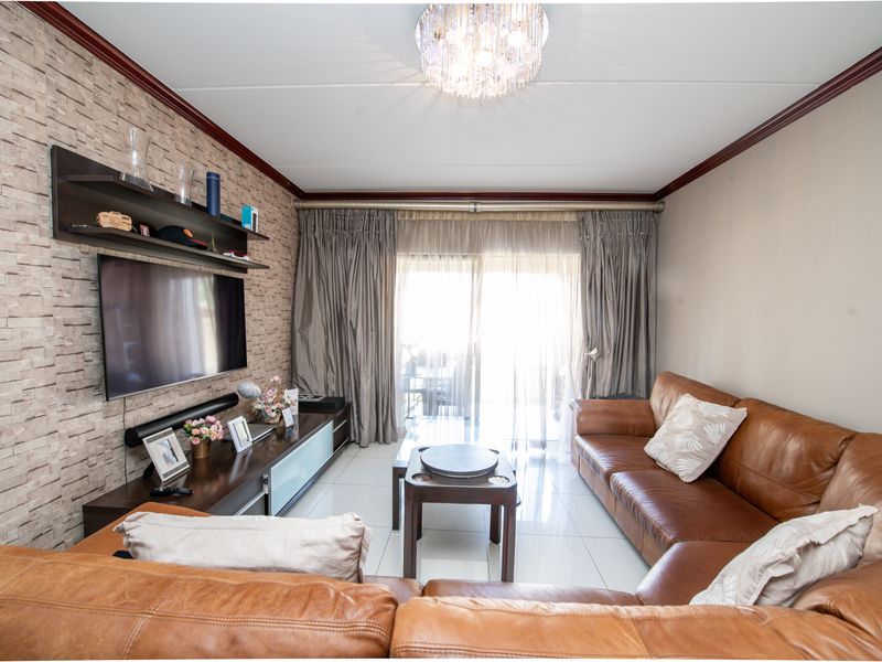 A well-maintained living room featuring tiled flooring, a textured feature wall, and a sliding glass door providing access to the outdoor area.