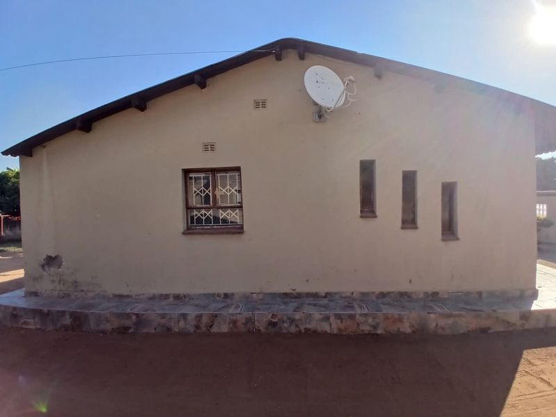 Rear exterior elevation of the house featuring a satellite dish, security bars on windows, and a tiled base plinth.