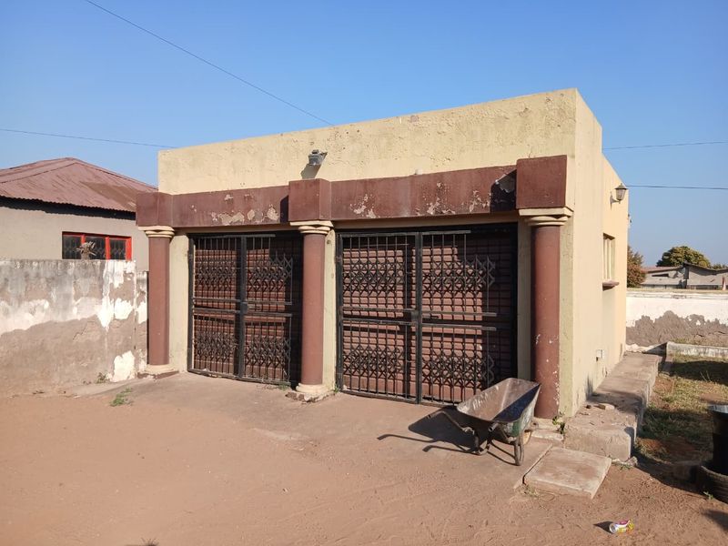 A detached double garage featuring decorative columns and security gates, showing signs of exterior wear and peeling paint.
