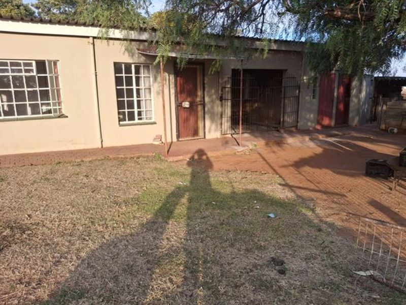 Rear exterior view of the property featuring a paved patio area, security gates, and metal roofing with access to the backyard.