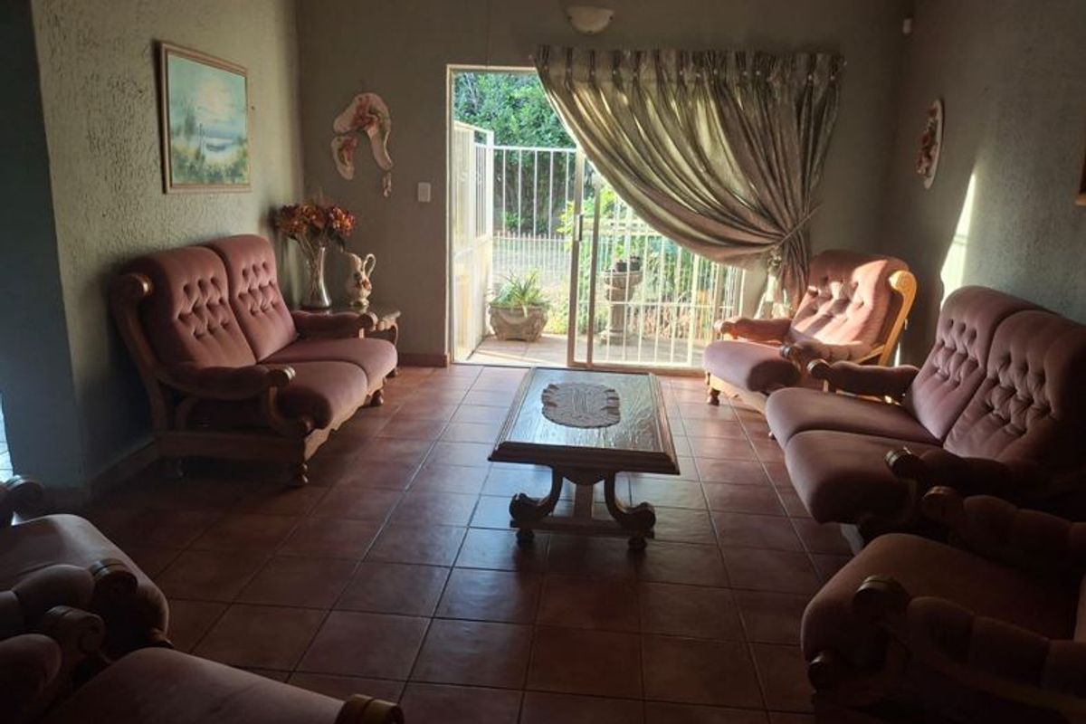 A living room featuring tiled flooring and a sliding glass door with an integrated security gate, providing direct access to the outdoor area.