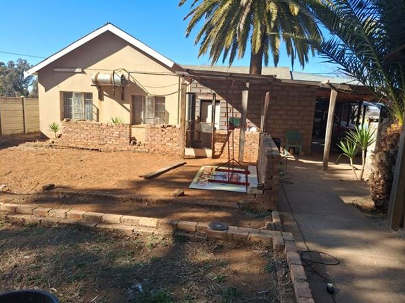 Rear exterior view of the farm property featuring a covered patio area, brick boundary walls, and an external geyser installation.