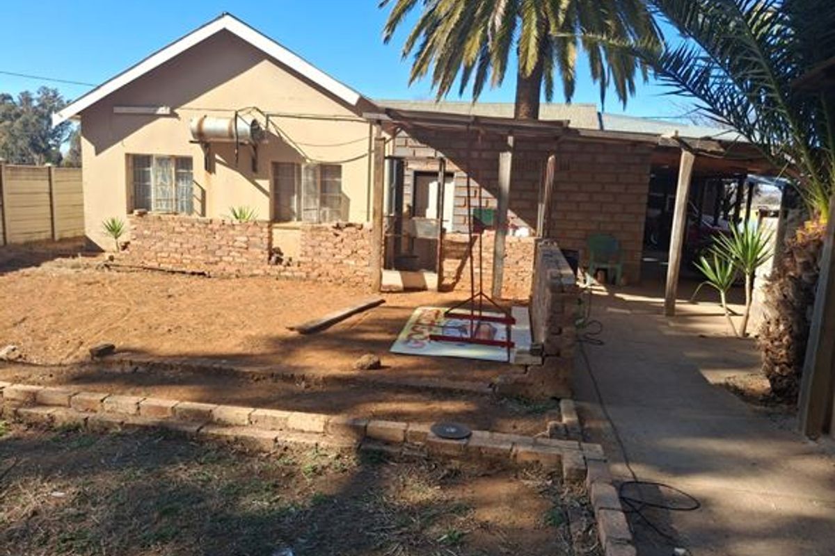 Rear exterior view of the farm property featuring a covered patio area, brick boundary walls, and an external geyser installation.