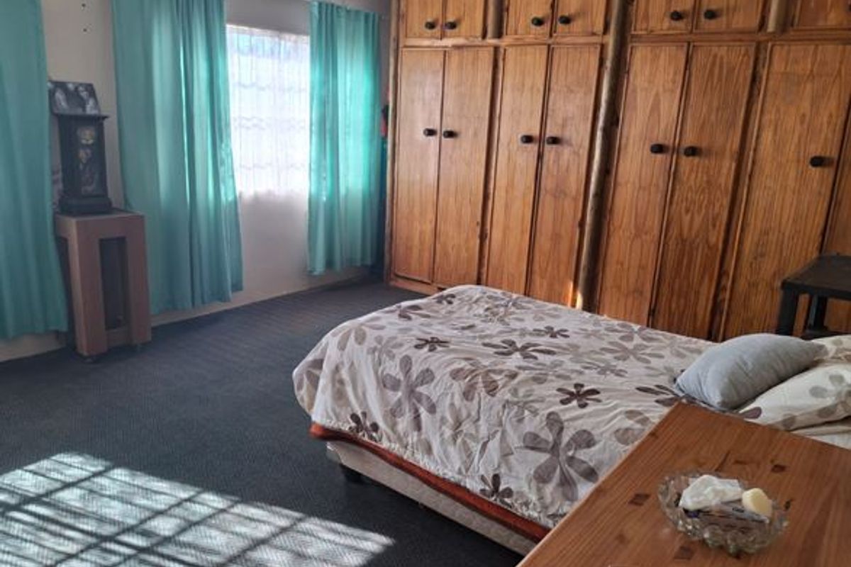 A bedroom featuring extensive built-in wooden cabinetry and carpeted flooring, offering ample storage space.
