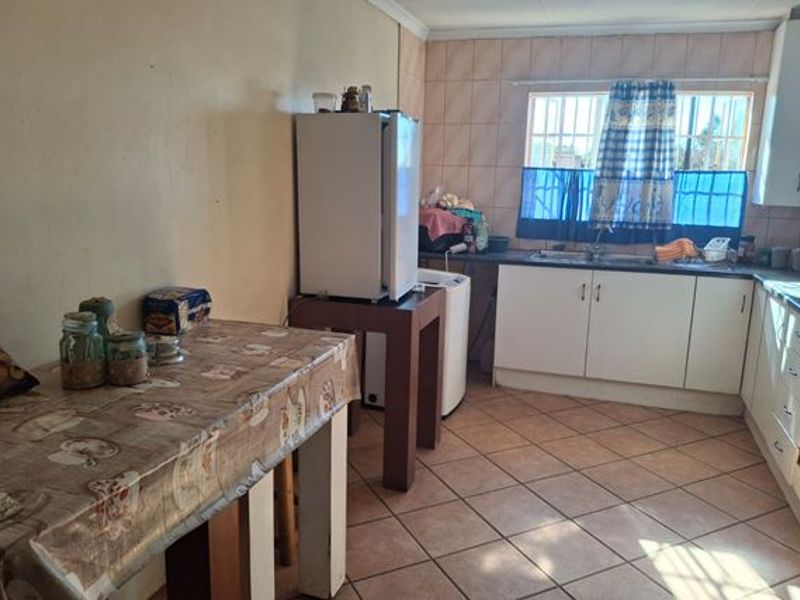 A functional kitchen featuring tiled flooring, built-in cabinetry, and a double sink, offering a practical layout with potential for modern cosmetic updates.