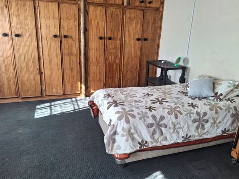 A bedroom featuring extensive built-in wooden cabinetry and dark carpeting.