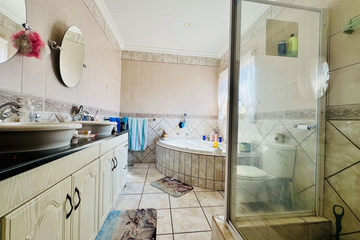Spacious bathroom featuring a corner soaking tub, glass-enclosed shower, and a double vanity with granite countertop.