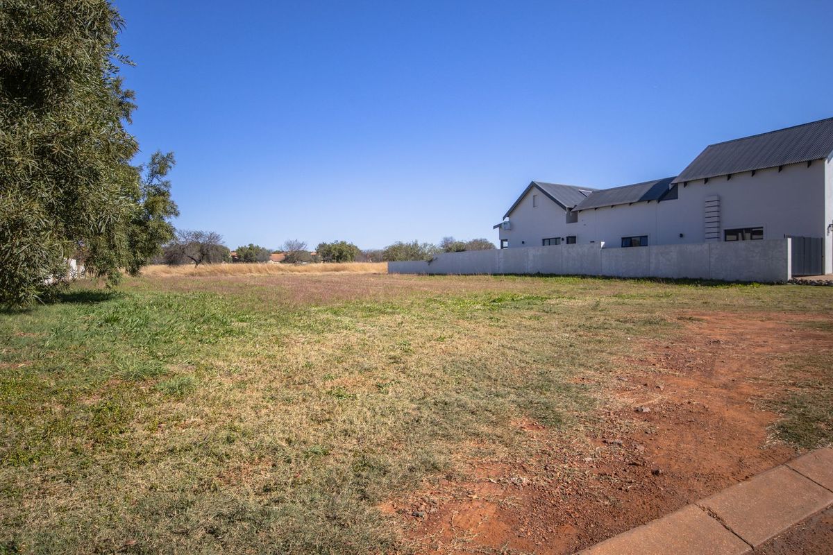 A vacant residential plot featuring level ground, established boundary walling, and direct street access in a developed neighborhood.