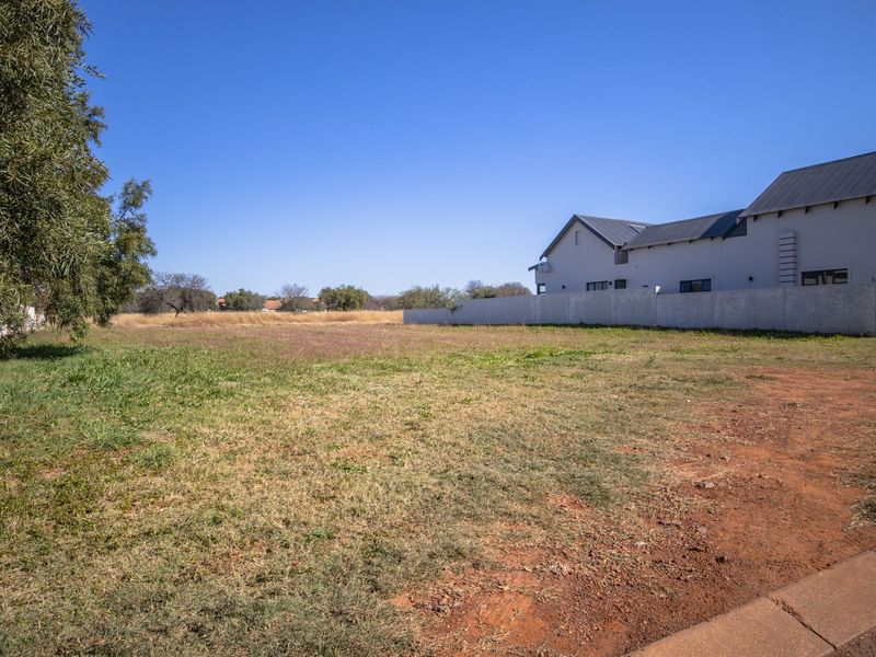 A vacant residential plot featuring level ground, established boundary walling, and direct street access in a developed neighborhood.