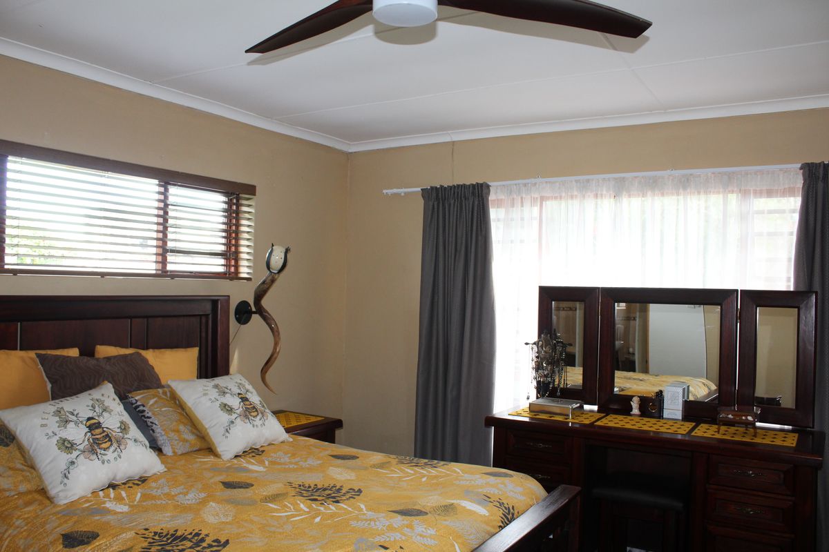 A bedroom featuring a ceiling fan, venetian blinds, and curtain tracks, with a visible wall crack requiring attention.