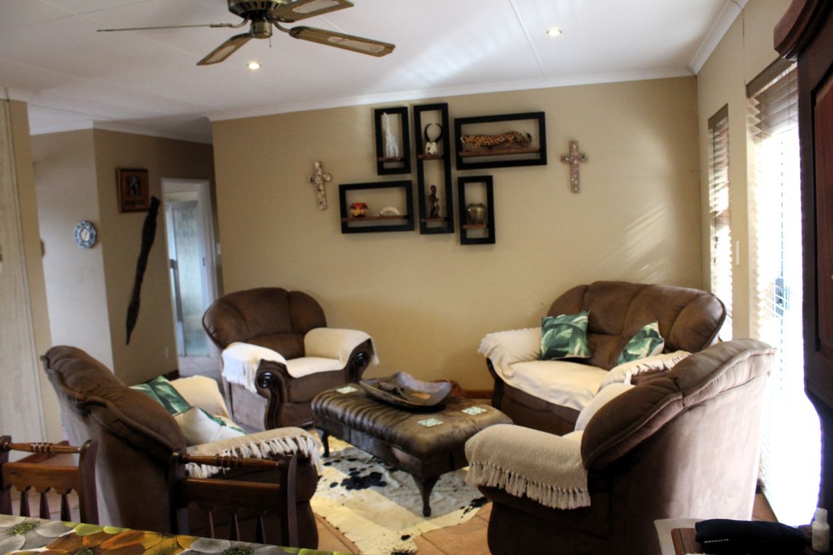 A comfortable living room featuring tiled flooring, recessed lighting, and a ceiling fan, with natural light entering through window blinds.