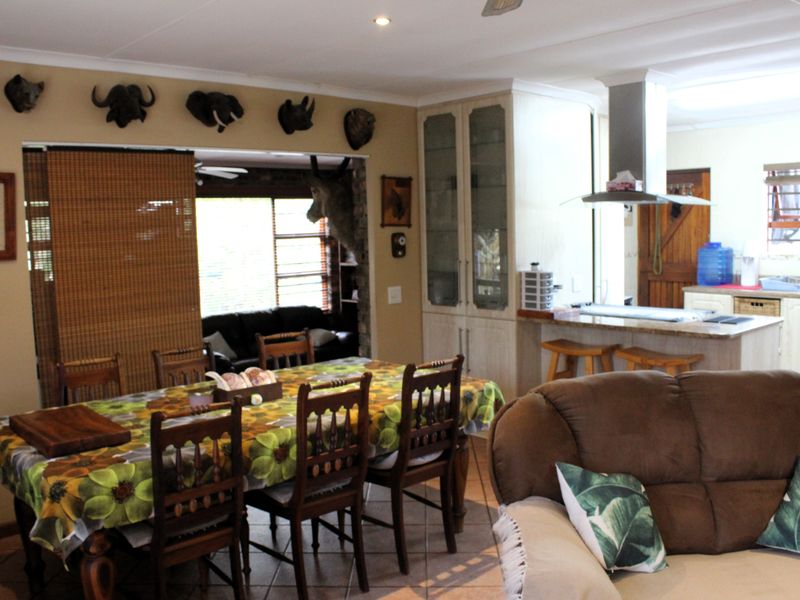 Open-plan living and dining area featuring a kitchen with built-in cabinetry, stone countertops, and a central island with an extractor fan.