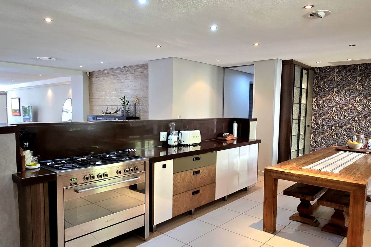 Modern open-plan kitchen featuring a large gas stove, sleek built-in cabinetry, and recessed lighting, seamlessly flowing into the adjacent living area.