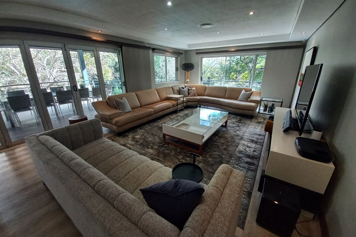 Spacious living room featuring recessed downlights, laminate flooring, and large sliding glass doors that provide ample natural light and access to the outdoor area.