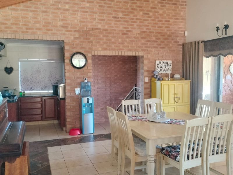 Open-plan dining and kitchen area featuring a vaulted timber ceiling, exposed brick feature wall, and tiled flooring with direct access to outdoor space.