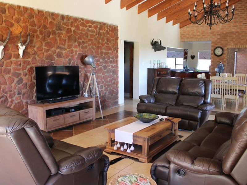 Spacious open-plan living and dining area featuring a striking stone feature wall, exposed brickwork, and high timber-beamed ceilings.